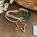 Vista detallada del collar de perlas multicapa con un gran colgante de estrella hueca dorada. - Estilo Estrella Perla (HN11926) / Oro azul blanco