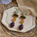 Detailed macro view of vintage multi-colored oval resin drop earrings with gold-tone edges. - Blue/Green/Purple