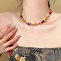 Detailed macro view of a handmade colorful beaded flower necklace worn by a female model - Necklace / Gold-Multicolor
