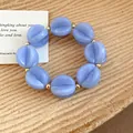 Lavender blue acrylic beaded bracelet with golden spacers shown on a textured wooden background. - Bracelet / Blue
