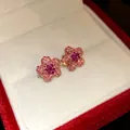 Macro detail of pink flower stud earrings with sparkling crystals in a velvet red jewelry box - Pink