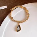 Detail view of a gold beaded bracelet with an irregular dark grey crystal pendant - Irregular Hammered Texture Bracelet / Gold