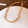 Detail view of a gold-toned necklace with irregular beads and a curved bar design. - Irregular Metal Beaded Clavicle Chain / Gold