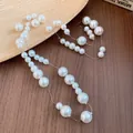 Close-up detail of a French vintage pearl necklace with varying bead sizes on wood - White