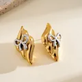 Detailed macro view of vintage gold stainless steel earrings with silver bow accents - Stud Earrings / Gold