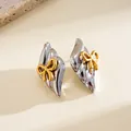 Detailed close-up of vintage silver stainless steel earrings with gold bow accents - Stud Earrings / Silver