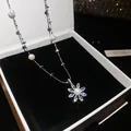 Close-up detail of elegant flower pendant necklace with shimmering zircons and pearls - Silver