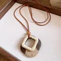 Close-up of a Maillard-style rhombic wooden pendant necklace with twine wrap detail. - Diamond Wood Handmade Woven Style