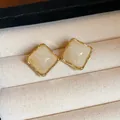 Macro view of vintage square resin stud earrings with gold frame in jewelry box - Diamond / Gold