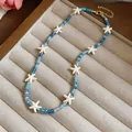 Gedetailleerde weergave van een blauwe kralenketting met witte zeesterren in een doos. - Blauw
