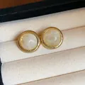 Close-up of vintage round earrings with cream marbled resin inlay and gold-tone frame - Smooth Round / Gold