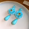 Vista dettagliata di orecchini a fiore in resina azzurra con ciondoli a goccia e perni in argento. - Stile Fiore Resina Goccia d'Acqua / Blu