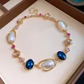 Dettaglio di una collana vintage dorata con cristalli blu e eleganti perle a goccia. - Collana (Oro-Blu-Bianco) / Oro