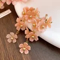 Close-up of pink acrylic flower tassel earrings with golden beads and steel needles - Pink