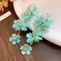Detailed close-up showing the mint green acrylic flower petals and gold chain dangle earrings. - Lake Blue