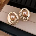 Vue détaillée de boucles d'oreilles dorées évidées avec perles de champagne sur un plateau - Style Perle Ronde Creuse / Or
