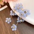 Detailed close-up of elegant light blue acrylic flower tassel earrings for women - Blue