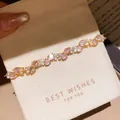 Close-up of elegant gold plated bracelet with pink zircons on a white gift pouch - 47# Bracelet