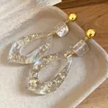 Macro detail shot of resin teardrop earrings with elegant gold foil flakes inside - Gold White