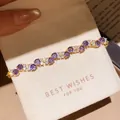 Detail view of elegant gold-plated bracelet with purple and white cubic zirconia flowers - 48# Bracelet