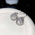 Close-up of elegant silver multi-layered circle earrings with sparkling zircon centers - Ear Hook (HE34320) / Silver