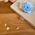 Detail view of a blue fabric flower hair clip with pearl tassels on a vintage book. - Duckbill Clip (42#)