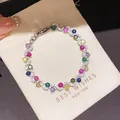 Elegant gold-plated bracelet with multi-colored zircons displayed on a cream gift pouch - Style 5 Bracelet