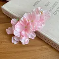 Primer plano de un clip de pelo con flor de tela rosa y perlas sobre un libro viejo. - Estilo Floral de Tela y Perlas Elegante (24#) / Pieza Única / Rosa