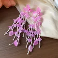 Detailaufnahme von eleganten rosa Glasblumenohrringen mit langen weißen Perlenquasten - Rosa