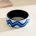 Close-up showing the intricate blue wave pattern on a chunky resin fashion bangle bracelet - Black Blue Wave