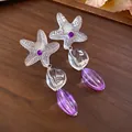 Detailed macro shot of clear resin starfish earrings with purple faceted beads. - White-Purple