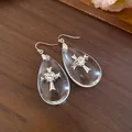 Detailed view of teardrop resin earrings featuring an intricate silver cross and heart motif - Silver