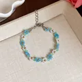 Gros plan d'un bracelet fleuri en perles de verre colorées aux accents estivaux - Bracelet / Blanc-Bleu
