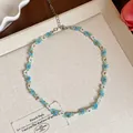 Gros plan d'un ras-du-cou en perles de verre avec de délicats motifs floraux bleus et blancs - Collier / Blanc-Bleu