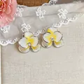 Dettaglio di orecchini a fiore in smalto bianco e giallo con pietra di zircone. - Fiore / Giallo