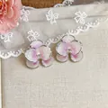 Primo piano di orecchini a lobo a fiore in smalto fatti a mano con sfumatura rosa e zircone - Fiore / Viola