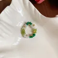 Gros plan détaillé d'une bague à fleurs en perles de verre colorées sur un plateau. - Bague / Blanc-Vert