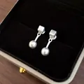 Dettaglio di orecchini pendenti in argento con perno quadrato e ciondolo a sfera. - Stile Geometrico Quadrato e Sfera / Argento