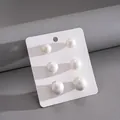 Vista dettagliata di tre paia di orecchini a perno con perle di diverse dimensioni - Set di 6 Orecchini a Bottone (HE34122) / Bianco