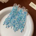 Close-up view of elegant blue and white glass bead tassel earrings on white ceramic - Silver Earring Post-Blue