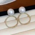 Primer plano de elegantes pendientes de aro con perlas y detalles de strass - Estilo Redondo (HE31776) / Oro-Blanco