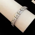 Detailed view of a stainless steel bracelet featuring cute enamel dog charms on a beige stand - Bulldog Style (TB163) / Silver