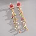 Close-up of pink enamel flower tassel earrings with pearls and colorful beads - Pink