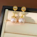 Detailed close-up of gold-plated clover pearl earrings with shimmering zircon accents - Gold (Pink Pearl)