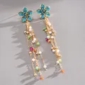 Detailed view of blue enamel flower tassel earrings featuring pearls and colorful beads - Blue