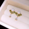Close-up of 14k gold plated stud earrings with pearls and green zircon accents - Waterdrop Stud Earrings (HE34200) / Gold With White Pearl Green Zirconia