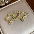 Primo piano di orecchini a stella a doppio strato dorati con finitura testurizzata - Oro - Stella