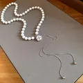 Detail shot of a white pearl necklace with a rhinestone flower pendant and tassels. - Camellia Tassel Style / Silver White