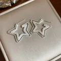 Primo piano di eleganti orecchini a lobo a stella in argento a doppio strato e texture - Argento-Stella
