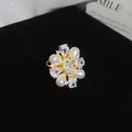 Detailed macro shot of a flower-shaped zircon and pearl open ring on black velvet. - Gold